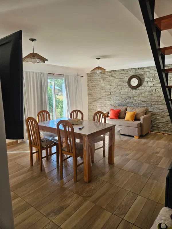 Living de la cabaña Campo, con pared de piedra, mesa de madera y sillón